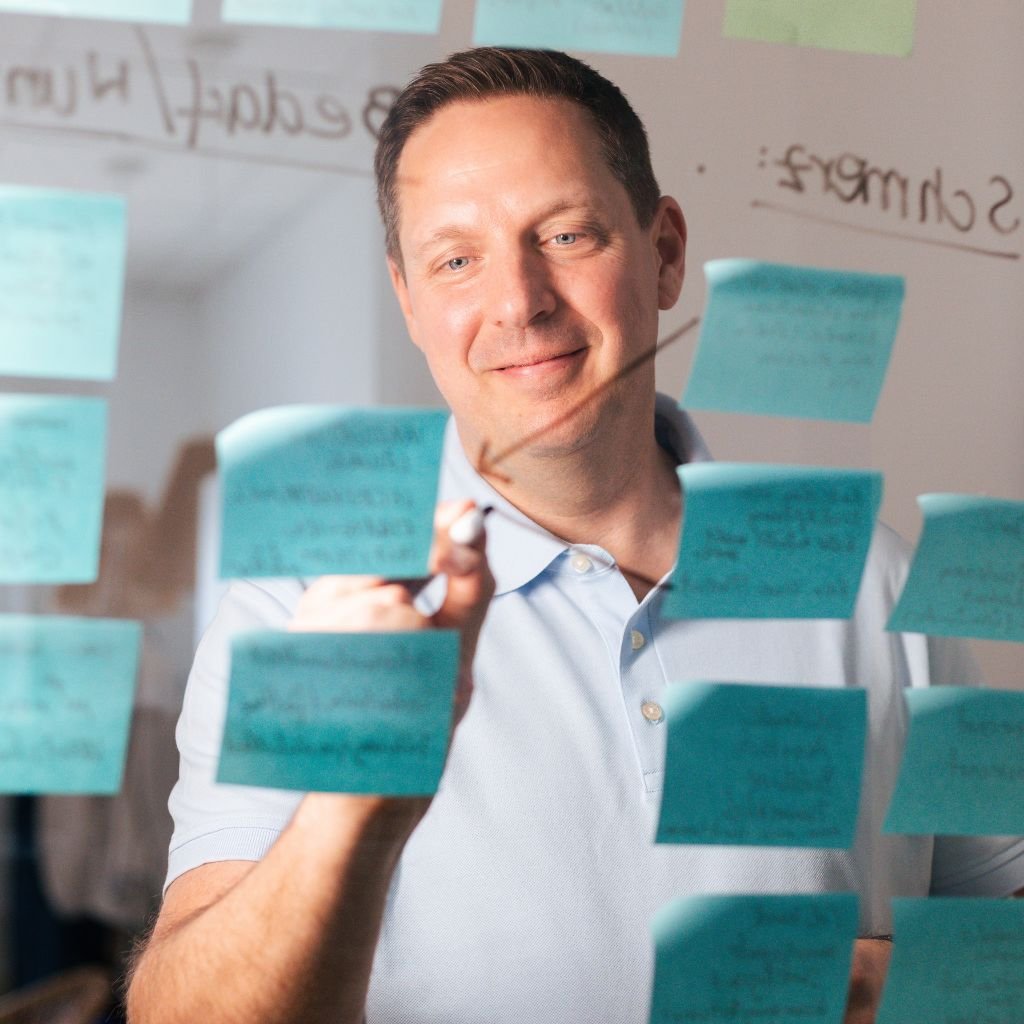 Leaderchip Coach Timo Pregler vor einer Scheibe mit Post its
